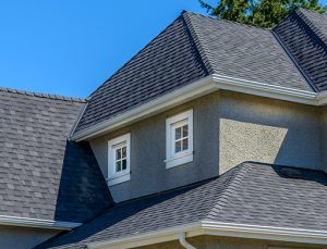 Photo of a gray asphalt shingle roof on a gray stucco house